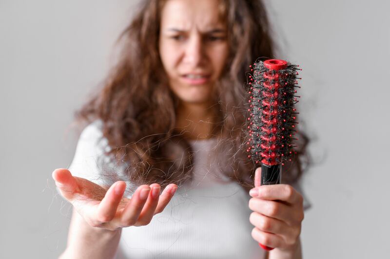 Mulher olhando para pente e cabelos nas mãos