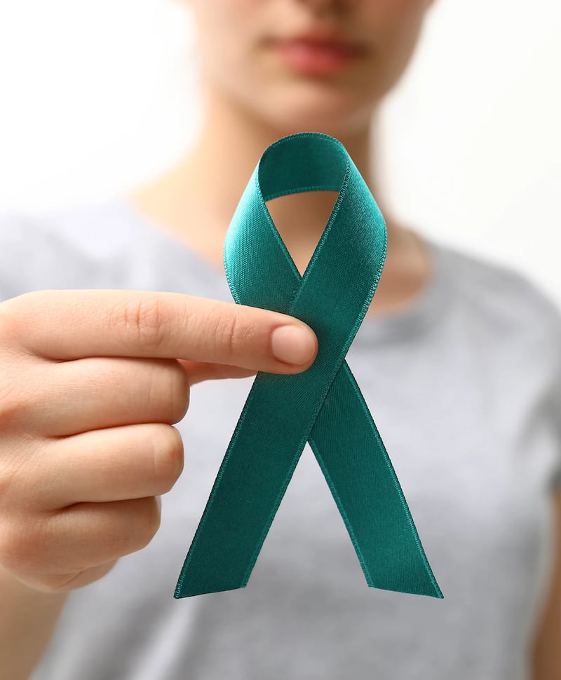 Una mujer sostiene un lazo color 'teal', o verde azulado, color que se utiliza como parte de la campaña de concientización sobre el cáncer cervical.